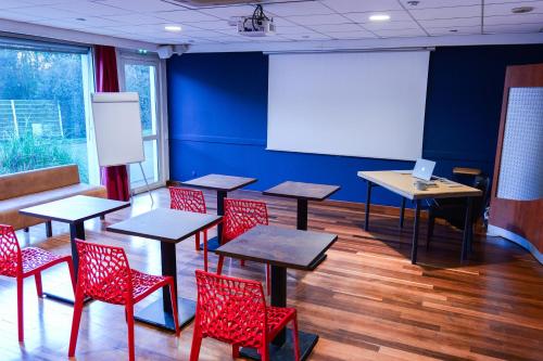 a classroom with tables and red chairs and a screen at Hôtel Les Genêts Bayonne in Bayonne
