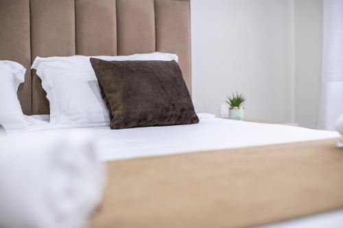 a bed with white sheets and a brown pillow at EKA Luxury Seaview Apartments in Vlorë