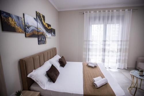 a bedroom with a bed with pillows and a window at EKA Luxury Seaview Apartments in Vlorë