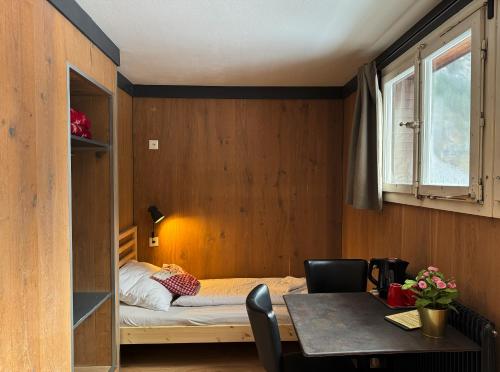 a small room with a bed and a table at Hotel Hornerpub in Lauterbrunnen