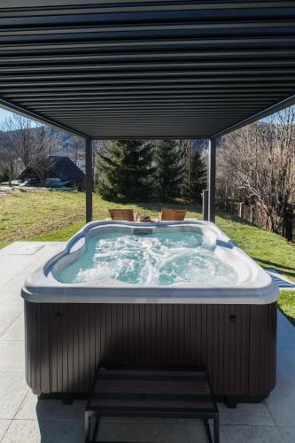 a jacuzzi tub with a bench under a cover at CASA NATURA - charming chalet with hot tub in Tuk Vojni