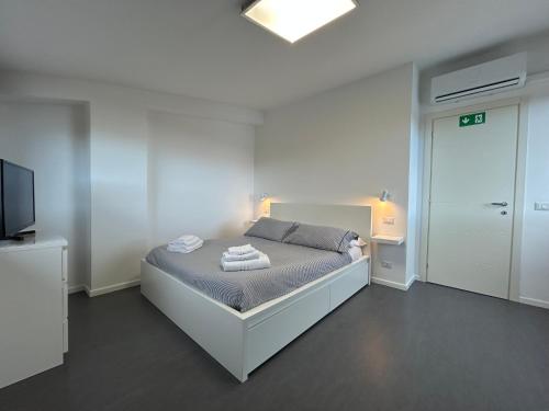a white bedroom with a bed and a television at Alloggio Buttero 12 in Maccarese