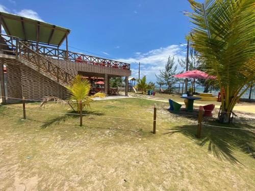 Casa ilha de Itaparica Aratuba 3 في Aratuba Beach: منتجع به مبنى وطاولة ونخلة