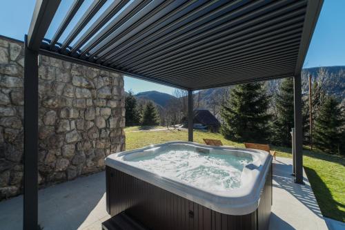 a hot tub on a patio with a stone wall at CASA NATURA - charming chalet with hot tub in Tuk Vojni