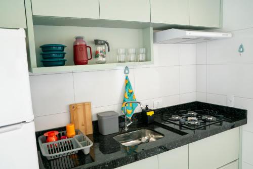 a kitchen counter with a sink and a stove at Alvorada do Lago - A melhor hospedagem de Umuarama in Umuarama