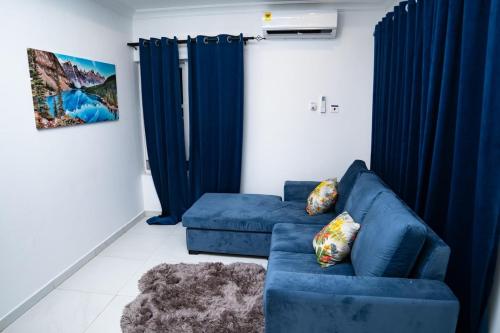 a living room with a blue couch and blue curtains at Ultimate Relaxation at H Village in Dawhwenya