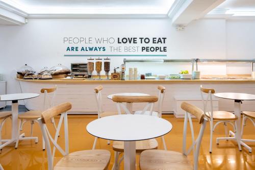 a room with tables and stools in front of a counter at Hotel Vibra Vila in Ibiza Town