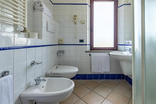 a white bathroom with two toilets and a sink at 1000 Miglia in Monteroni dʼArbia
