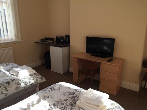 a room with two beds and a desk with a television at Hardwick Hotel in Horden