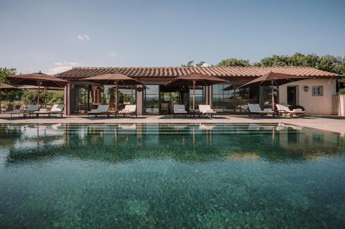 a pool of water with chairs and umbrellas at Il Borro Relais & Châteaux in San Giustino Valdarno