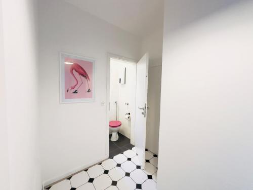 a bathroom with a pink toilet and a black and white tile floor at Möbliert-nahe STARLIGHT EXPRESS in Bochum -WLAN-Netflix-Loggia oder Terrasse in Bochum