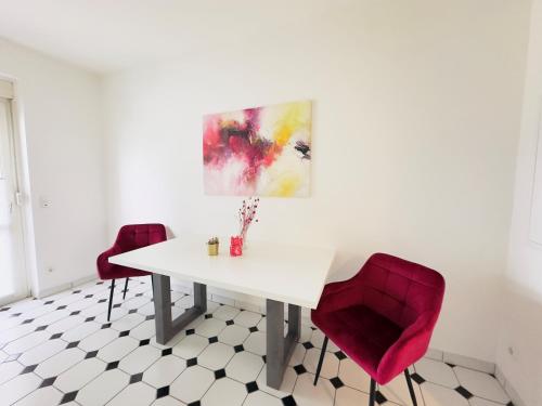 a dining room with a white table and two red chairs at Möbliert-nahe STARLIGHT EXPRESS in Bochum -WLAN-Netflix-Loggia oder Terrasse in Bochum