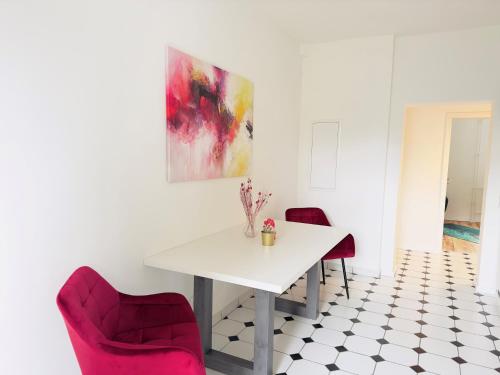 a dining room with a white table and two red chairs at Möbliert-nahe STARLIGHT EXPRESS in Bochum -WLAN-Netflix-Loggia oder Terrasse in Bochum