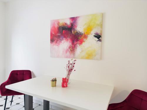a white table with a painting on the wall at Möbliert-nahe STARLIGHT EXPRESS in Bochum -WLAN-Netflix-Loggia oder Terrasse in Bochum