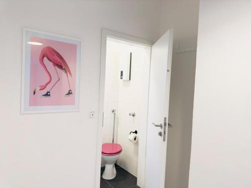 a bathroom with a toilet and a pink stool at Möbliert-nahe STARLIGHT EXPRESS in Bochum -WLAN-Netflix-Loggia oder Terrasse in Bochum