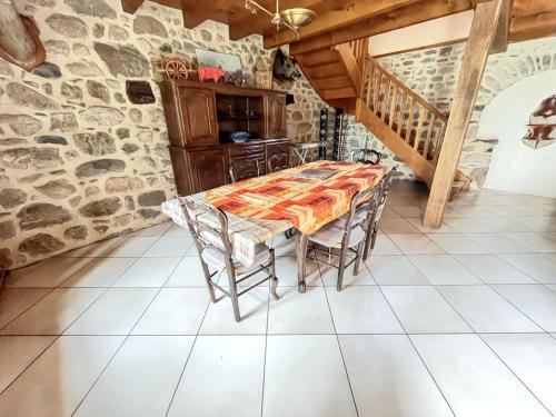 a table and chairs in a room with a stone wall at Maison cosy à Lanobre + Jardin in Lanobre