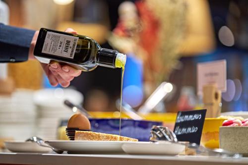a person holding a bottle of wine over a table at Novotel Rouen Centre Cathédrale in Rouen