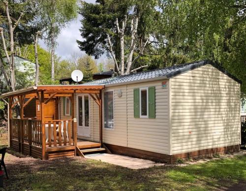 une petite cabine avec une terrasse couverte et une terrasse dans l'établissement Oree du bois, à Besse-et-Saint-Anastaise