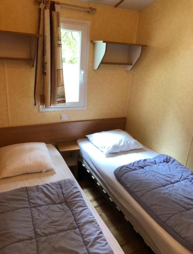 deux lits dans une petite pièce avec une fenêtre dans l'établissement Oree du bois, à Besse-et-Saint-Anastaise
