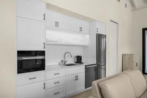 a kitchen with white cabinets and a stainless steel refrigerator at Ambergris Cay - Private Island All-Inclusive in Big Ambergris Cay