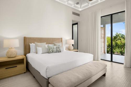 a white bedroom with a large bed and a window at Ambergris Cay - Private Island All-Inclusive in Big Ambergris Cay