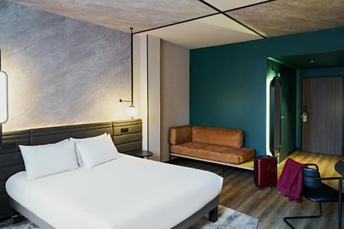 a hotel room with a bed and a chair at Novotel Rouen Centre Cathédrale in Rouen