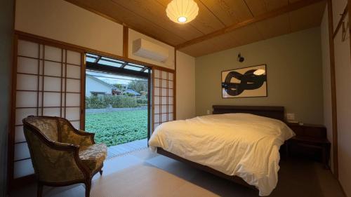 ein Schlafzimmer mit einem Bett, einem Fenster und einem Stuhl in der Unterkunft 一棟貸切の和風プライベートヴィラ プール花火バーベキュー in Fukutsu