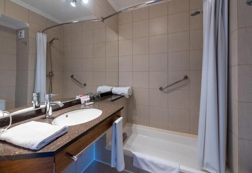 um banheiro com pia e chuveiro em Hotel Cabaña Del Lago Puerto Varas em Puerto Varas