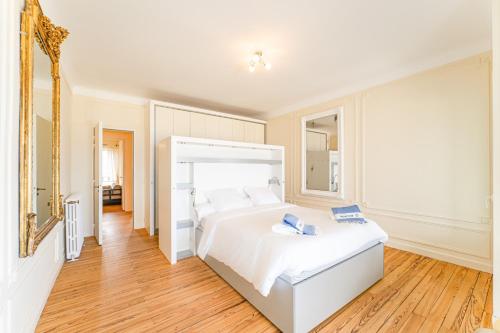 une chambre blanche avec un grand lit et un miroir dans l'établissement Somptueuse demeure Arcachonnaise de caractère avec accès direct à la plage, à Arcachon