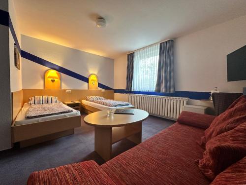 a hotel room with a couch and a bed and a table at Zeitwohnen Wolfsburg, ehemals Hotel am Klieversberg ein Unternehmen der Micha'S Hotelbetriebe in Wolfsburg