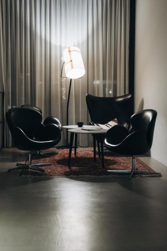 a living room with two chairs and a table and a lamp at Design Hotel Tyrol in Rablà