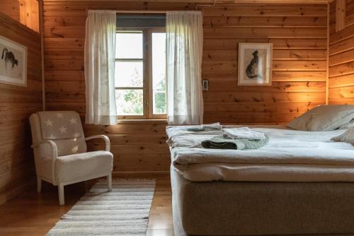 a bedroom with a bed and a chair and a window at Ireneborg, cottage with Finnish sauna in Svedja
