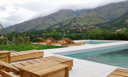 a swimming pool with chairs and a view of mountains at Parque Los Nogales Apart Hotel in Merlo
