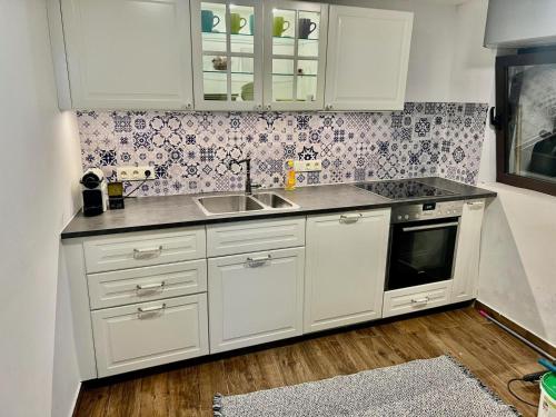 a kitchen with white cabinets and a sink at Steinhaus im Zentrum, 50 m zum Meer in Baška