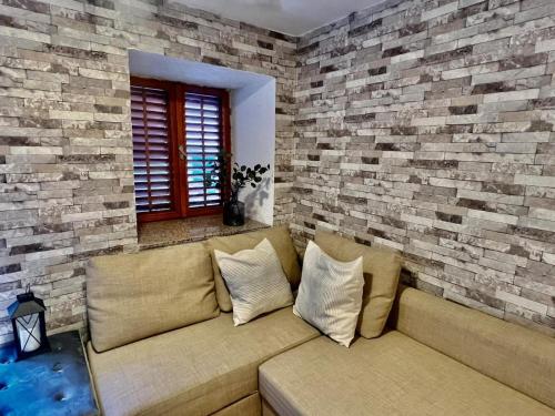a couch in a living room with a brick wall at Steinhaus im Zentrum, 50 m zum Meer in Baška