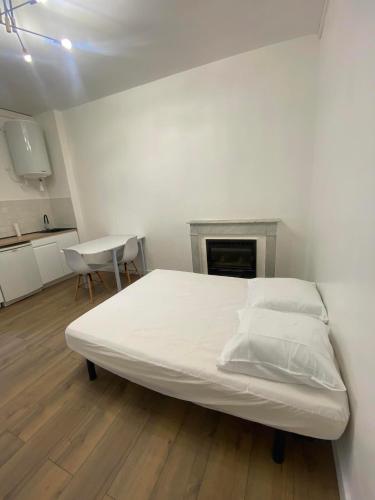 - un lit blanc dans un dortoir doté d'une cheminée dans l'établissement Charmant studio en centre-ville, à Corte