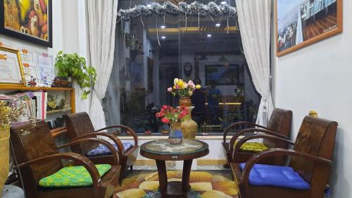 a table with chairs and a vase of flowers on it at NEST House in Ấp Kim Thạch