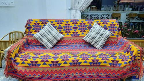 a colorful couch with two pillows on it at NEST House in Ấp Kim Thạch