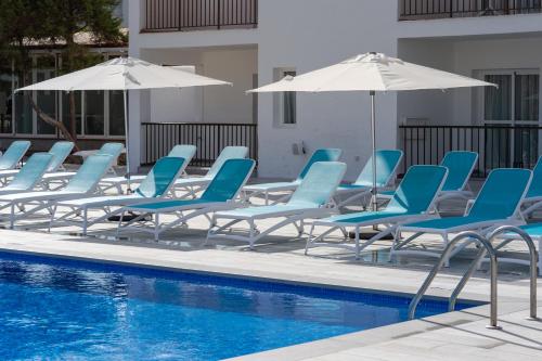un grupo de sillas y sombrillas azules junto a una piscina en Aparthotel Vibra Club Maritim, en Bahía de San Antonio