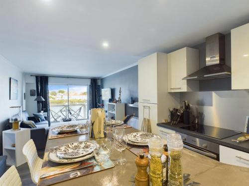 une cuisine avec une table avec des assiettes et des verres dessus dans l'établissement Appartement cosy pour 4, vue sur la Vie, à Saint-Gilles-Croix-de-Vie