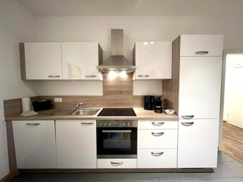 a kitchen with white cabinets and a sink and a stove at Zentrales City-Appartment in Bayreuth