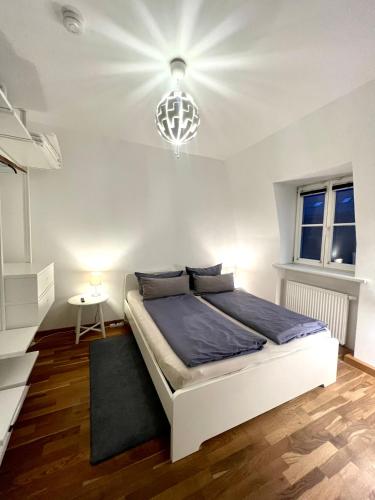 a bedroom with a white bed and a chandelier at Zentrales City-Appartment in Bayreuth