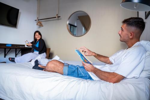 a man laying on a bed reading a book with a woman at Jungle House in Las Palmas de Gran Canaria