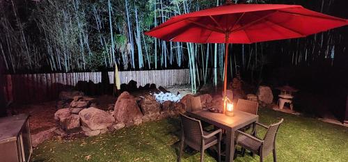 a table with a red umbrella in a backyard at あかがね荘別邸 in Sumino