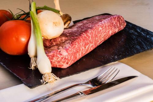 a piece of meat on a cutting board with vegetables at Park Plaza Trier in Trier