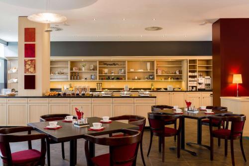 a restaurant with tables and chairs and a kitchen at Park Plaza Trier in Trier
