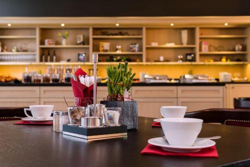 a table with two white cups and plates on it at Park Plaza Trier in Trier