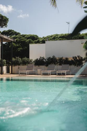 a swimming pool with lounge chairs next to a building at Casa Cuatro Boutique Hotel - Adults Recommended in Novo Sancti Petri
