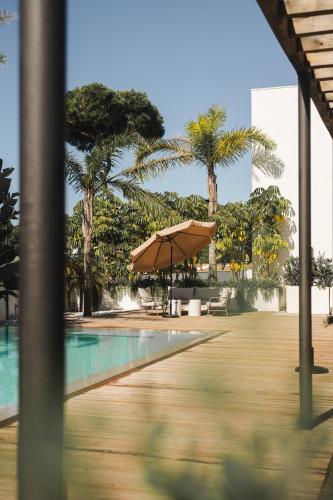 a swimming pool with an umbrella and palm trees at Casa Cuatro Boutique Hotel - Adults Recommended in Novo Sancti Petri