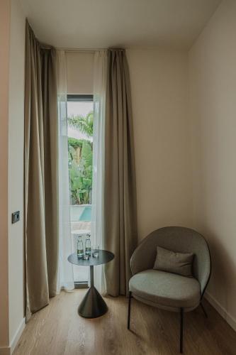 a chair and a table in front of a window at Casa Cuatro Boutique Hotel - Adults Recommended in Novo Sancti Petri
